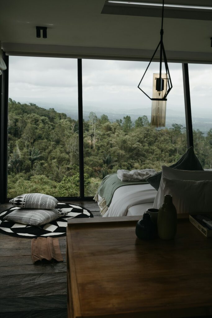 Cozy bedroom with large windows overlooking a forest — ideal Airbnb cabin setting