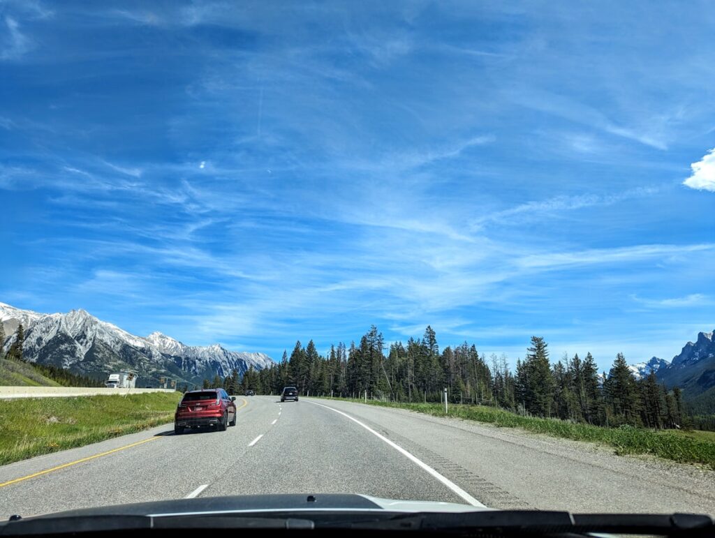 Car driving on an open highway through mountains on a budget road trip