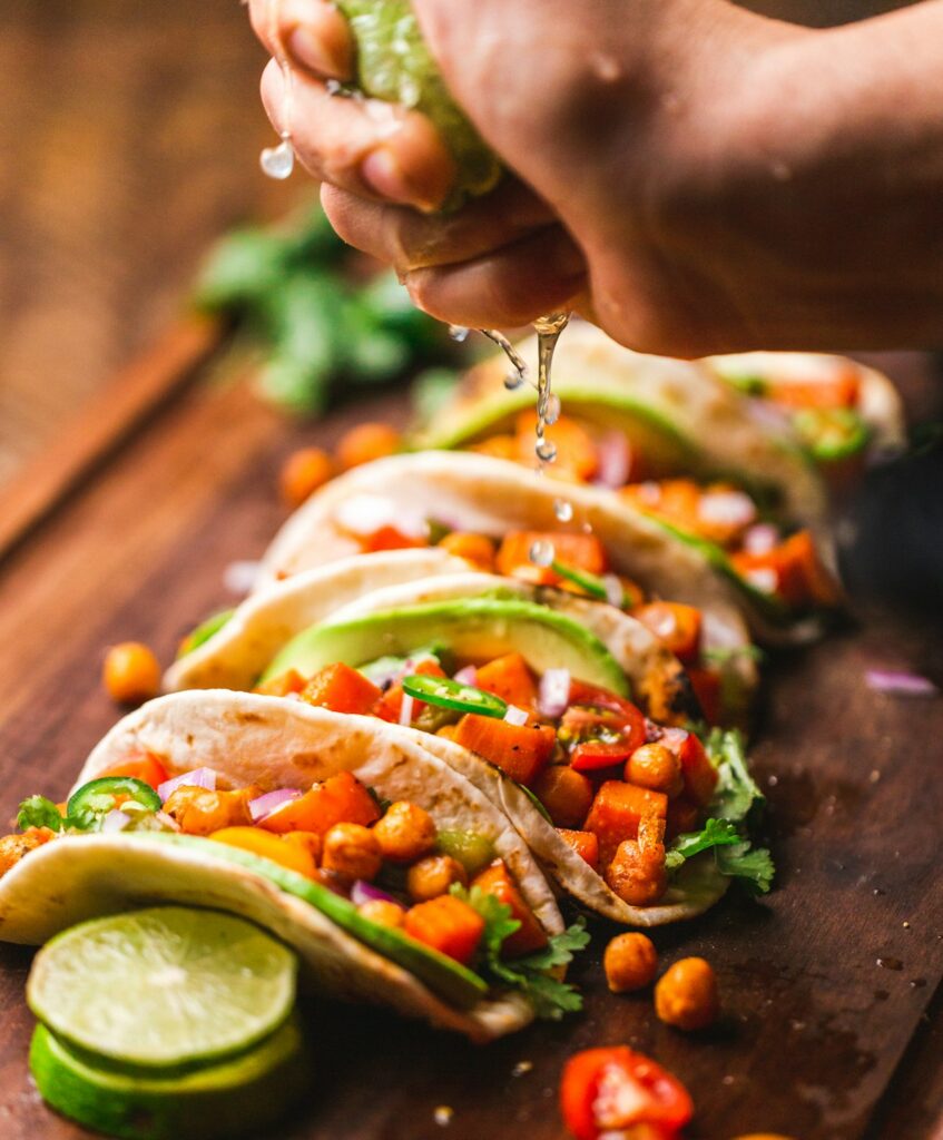 Person holding a plate of colorful street tacos from a local food vendor while traveling