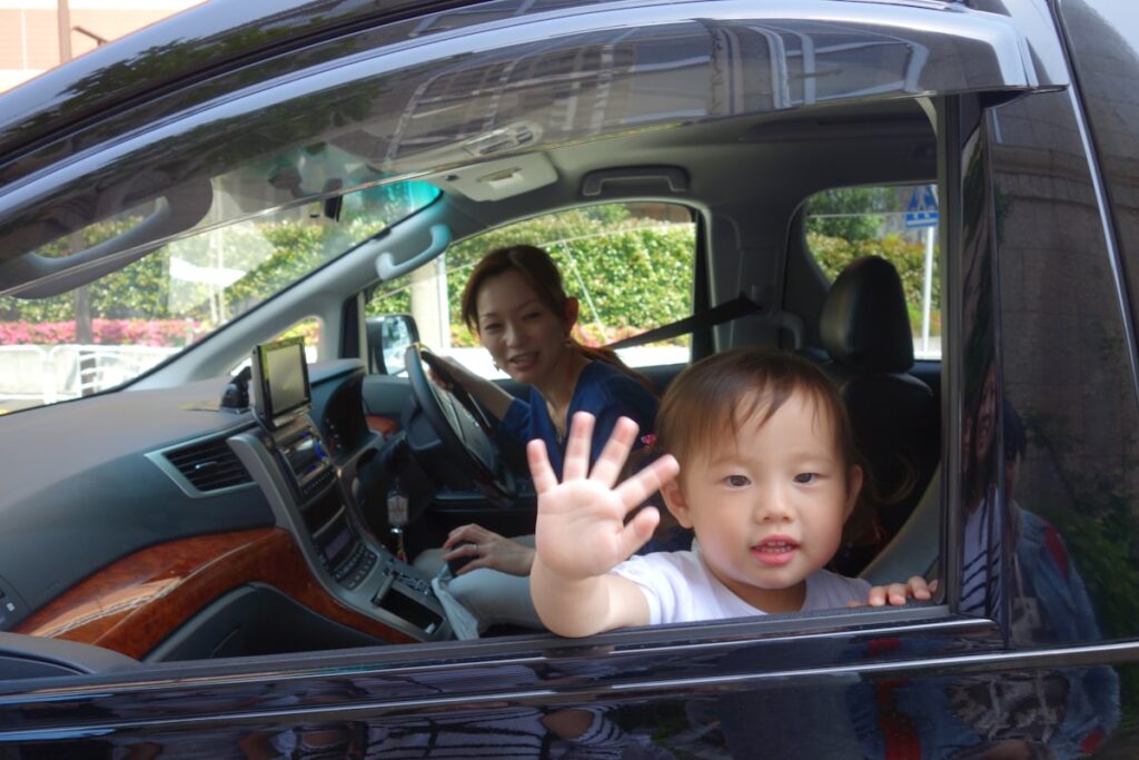 Child waving from car window on a family road trip