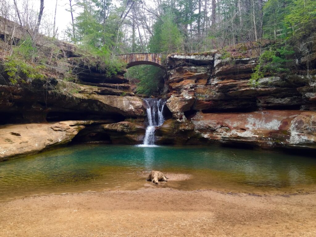 Woman sitting on a rock beside a waterfall at Hocking Hills State Park, Ohio