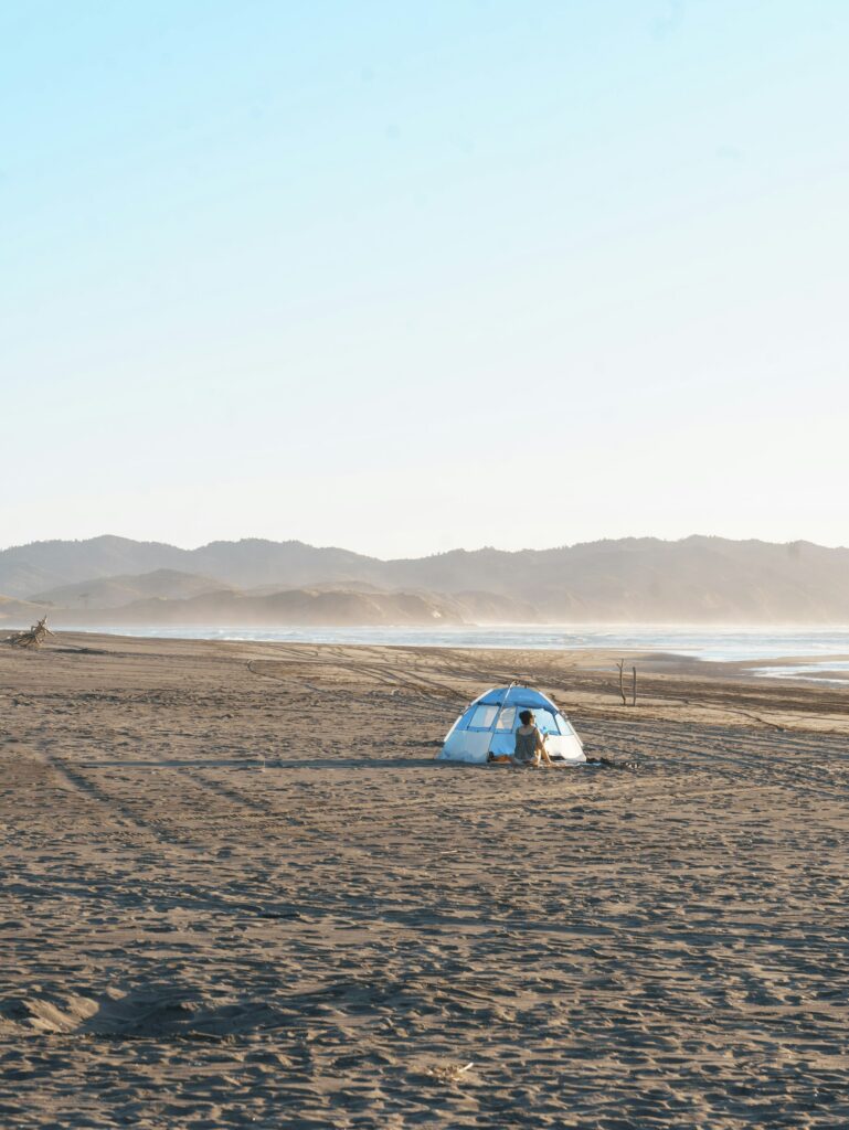 Cheap beach camping tent pitched on a sandy oceanfront beach at sunset