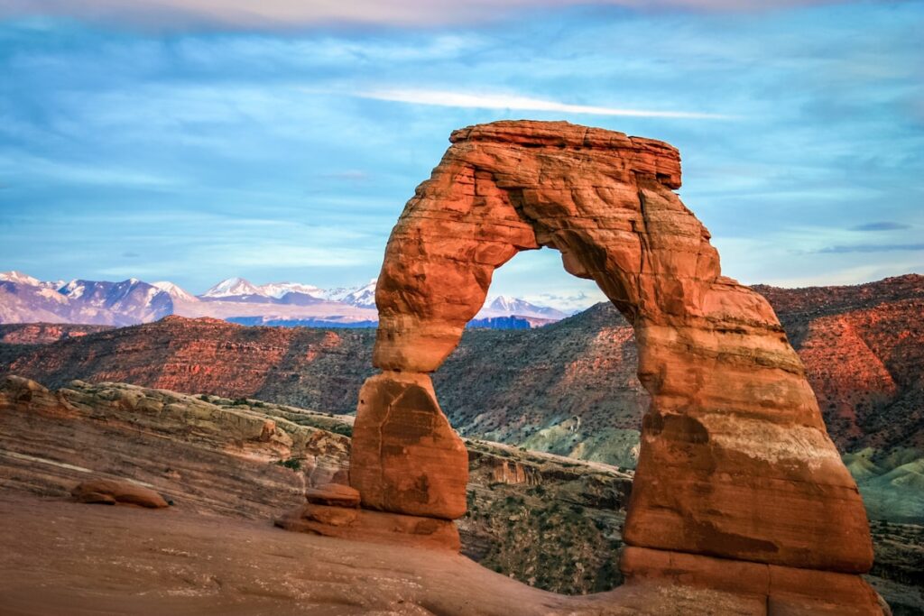 Cost to visit Arches and Canyonlands: Delicate Arch glowing at sunset in Arches National Park, Utah