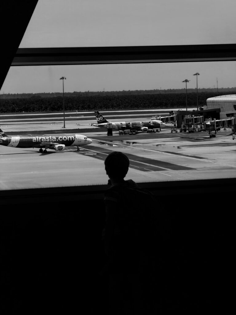 When do kids fly free: a child watches airplanes through an airport window before a flight