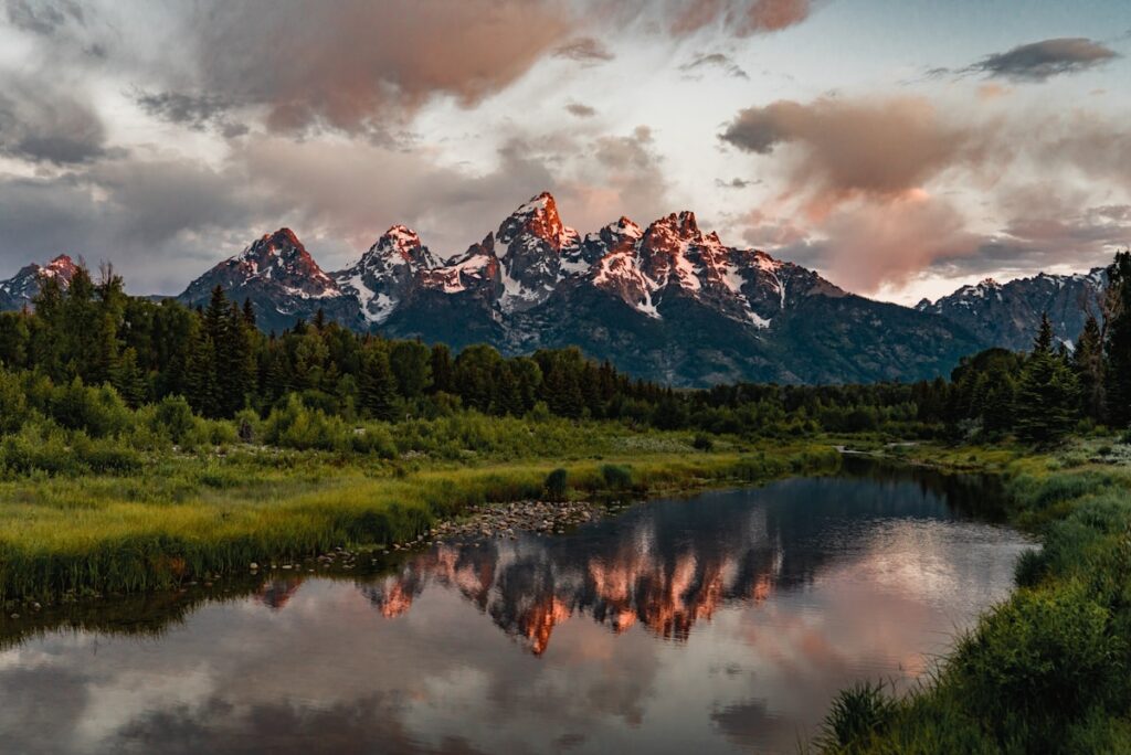 Cost to visit Grand Teton: snow-capped Teton peaks reflected above an alpine lake at sunrise