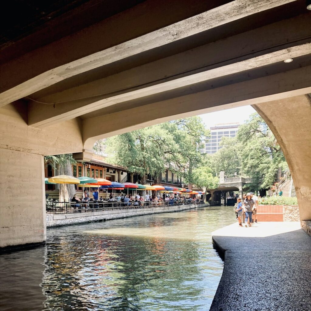 Cheap Labor Day getaways: colorful umbrellas over riverside dining on the San Antonio River Walk