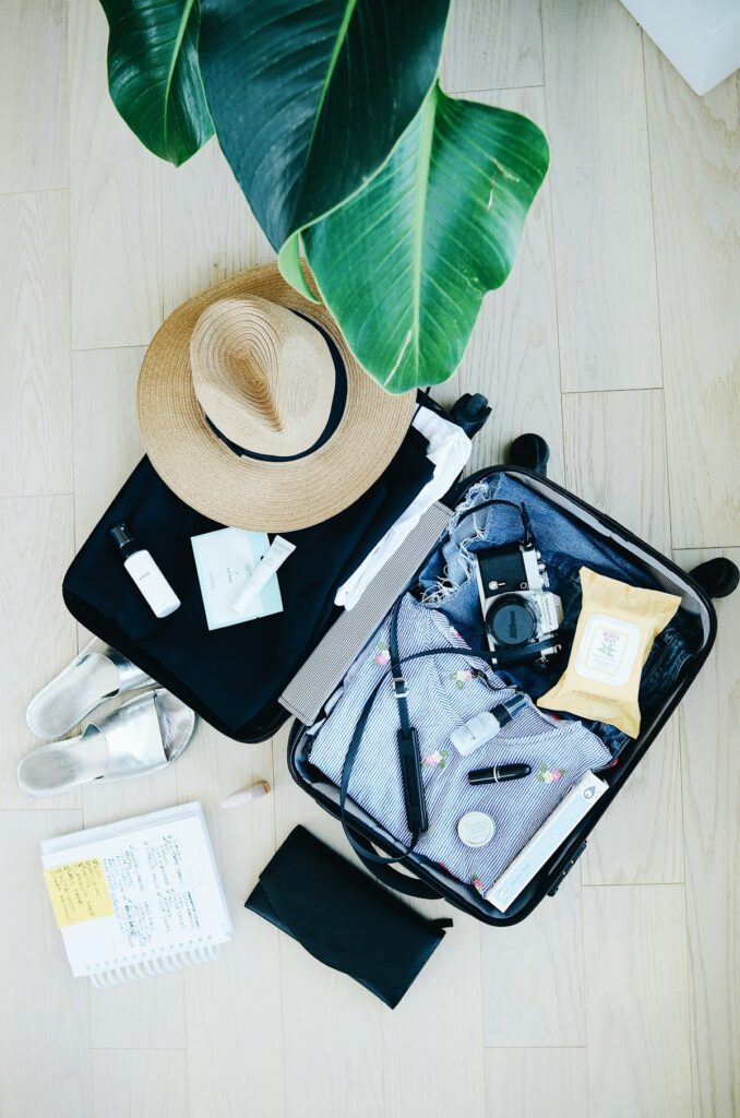 Budget travel gear laid out in an open suitcase with a hat and travel essentials